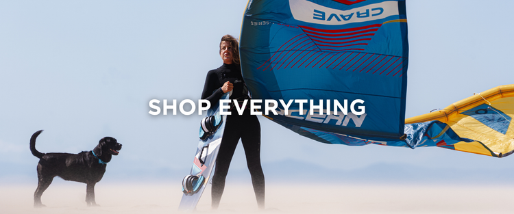 Ocean Rodeo Shop Everything hero banner. Image shows a woman in a black wetsuit holding an Ocean Rodeo Crave kite on a beach, with a black labrador next to them. The text says 'Shop Everything'. 